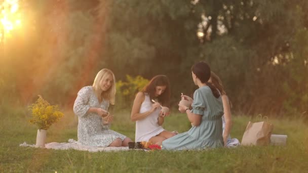 Um grupo de jovens mulheres na natureza, em uma área aberta ao pôr do sol à noite estão esculpir de barro, usando ferramentas, decorando produtos, comunicando, compartilhando impressões, alegrando-se com os resultados.. — Vídeo de Stock