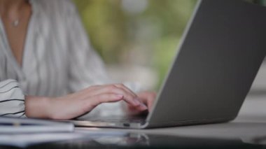 Yazlık bir kafede otururken dizüstü bilgisayarda yazı yazan bir kadının yakın çekimi. Serbest çalışan birinin uzaktan kumandası. Bilgisayar kodunu yazdır