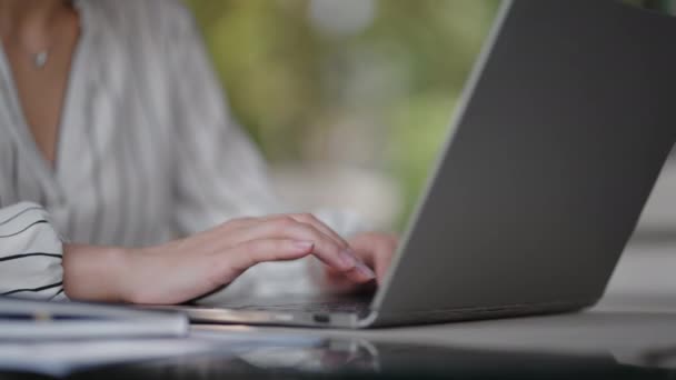 Κοντινό πλάνο μιας γυναίκας που πληκτρολογεί σε ένα πληκτρολόγιο φορητού υπολογιστή ενώ κάθεται σε ένα καλοκαιρινό καφέ. Απομακρυσμένη δουλειά ελεύθερου επαγγελματία. Εκτύπωση κώδικα υπολογιστή — Αρχείο Βίντεο