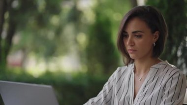 İş kadını esmer, Arap kökenli Latin kökenli bir grup, bir yaz kafesinde uzaktan kumandalı iş yaparken dizüstü bilgisayarda yazı yazıyor. Serbest çalışan kadın. Küçük işletme