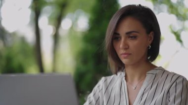 İş kadını esmer, İspanyol kökenli, güneşli bir günde bir yazlık kafede otururken uzaktan çalışıyor..