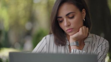 Düşünceli, esmer, Arap kökenli, Latin kökenli bir kadın bir yazlık kafede dizüstü bilgisayarlı bir masada oturuyor. Ciddi iş kadını problem çözme ve iş geliştirme stratejisi üzerine kafa yoruyor