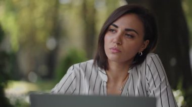 Yetenekli Ciddi Esmer Kadın Arap Latin kökenli grup bir yaz kafesinde dizüstü bilgisayarla bir masada oturuyor. Sorunları çözmeyi düşünüyor. Kafası karışmış iş kadını. Güzel bir iş kadınının portresi.