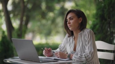 Yetenekli Ciddi Esmer Kadın Arap Latin kökenli grup bir yaz kafesinde dizüstü bilgisayarla bir masada oturuyor. Sorunları çözmeyi düşünüyor. Kafası karışmış iş kadını. Güzel bir iş kadınının portresi.