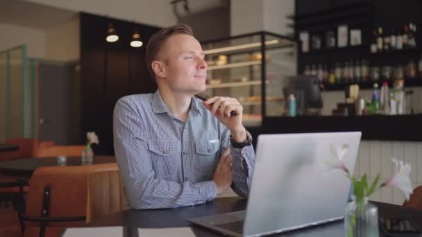 Großaufnahme Porträt des grübelnden jungen Mannes im Amt. Designer plant seine Arbeit und hält einen Bleistift in der Hand. Schießen ist Zeitlupe von unten. Nachdenklicher seriöser Mann sitzt mit Laptop-Denklösung — Stockvideo