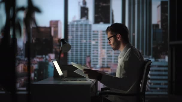 Portrait d'un homme d'affaires réfléchi et prospère travaillant sur un ordinateur portable dans son bureau de la grande ville la nuit. Charismatic Digital Entrepreneur effectue une analyse de données pour sa stratégie de commerce électronique — Video