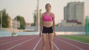 Bayan sporcu koşuya koşu parkurunda başlıyor. Koşucu koşu parkurundan kalkıyor. Genç bayan sporcu bloktan koşmaya başladı. Yavaş çekim,