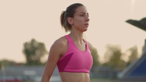 Vrouwelijke atleet begint haar sprint op een hardloopbaan. Runner stijgt op vanaf de startblokken op de renbaan. Jonge vrouw atleet beginnen te lopen van blok. Langzame beweging, — Stockvideo