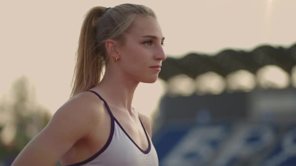 Vrouwelijke atleet begint haar sprint op een hardloopbaan. Runner stijgt op vanaf de startblokken op de renbaan. Jonge vrouw atleet beginnen te lopen van blok. Langzame beweging, — Stockvideo