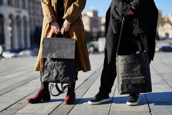 People holding black eco paper made bag and backpack on the city street background. Fashion recycled paper bags concept.