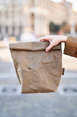 Şehir manzarasının arka planında el ele tutuşma kağıdı. Eko beslenme çantası. Öğle yemeği konsepti