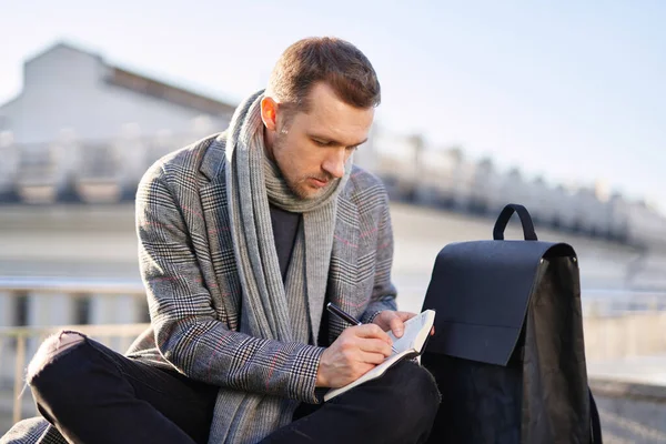 Beyaz sakallı, atkılı, gri ceketli, açık havada notlar alan bir adam. Güneşli bir bahar ya da sonbahar gününde erkek gibi düşünmek ve çalışmak. Çalışma ve öğrenim kavramı