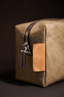 Yeniden kullanılabilir kağıt konsepti. Siyah zemin üzerinde metal fermuar ve kahverengi etiketli yeşil sıfır atık kağıt seyahat kozmetik kesesi