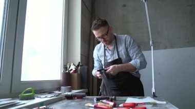 Önlüklü bir adam, iş yerindeki düşman linocut atölyesini hazırlıyor. Taş baskı sanatı yapmak için el yapımı sanat yeri. 4k görüntü