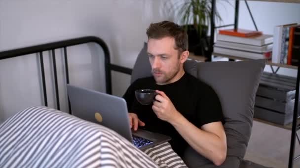 いつもオンラインだ 白人の髭を生やした男がベッドでノートパソコンで働いていた 早朝だ 隔離中のオンライン学習 作業やショッピングの概念 4K映像 — ストック動画