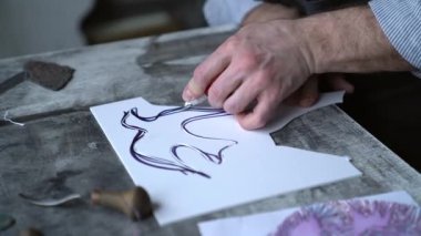 Linocut sanatçısı el yapımı oyma işlemi yapıyor. Önlük konusunda uzman profesyonel taşbaskı uzmanı. Kesici alet kullanarak linocut yapıyor. 4k görüntü