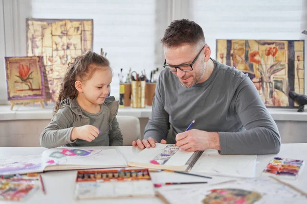 Dad helping child daughter to draw together with crayons