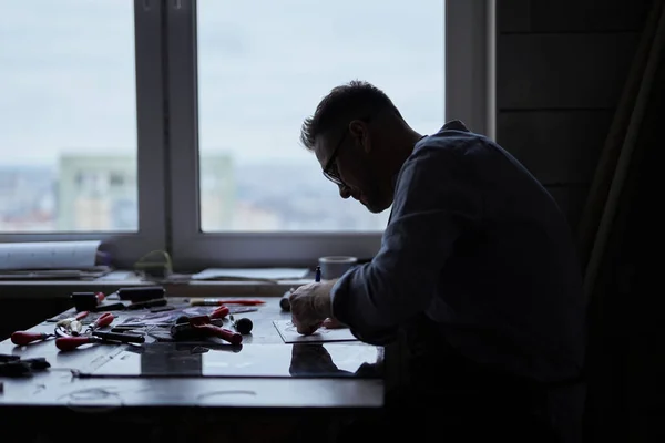 Silhouette of artist at working place in front of window