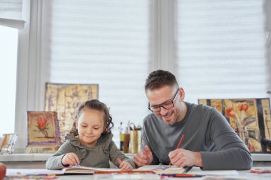 Mutlu baba ve kız pastel boyalarla resim çiziyor.
