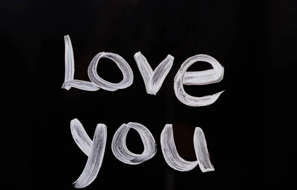 Text message Love you on glass using brush and paint