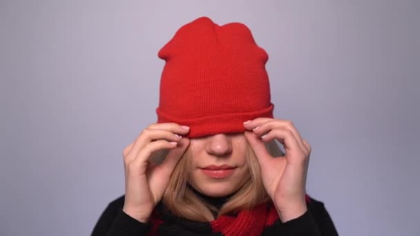 Piękna radosna blondynka podciągająca i opuszczająca czerwony kapelusz — Wideo stockowe