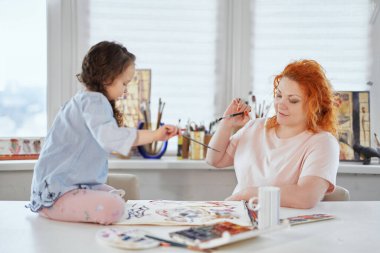 Mutlu anne kızıyla suluboya resim çiziyor.