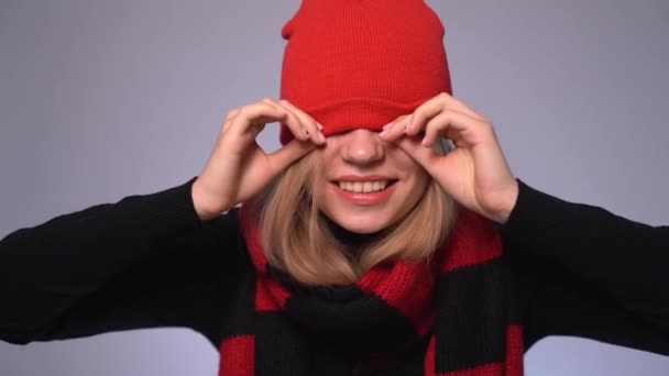 Rubia divertida joven hembra tirando hacia arriba y hacia abajo sombrero rojo — Vídeos de Stock