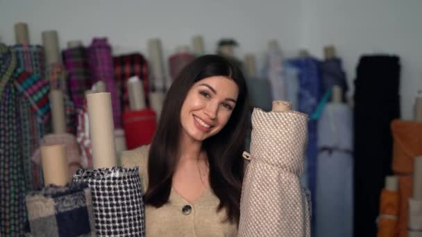 Glimlachende vrouw ontwerper, op maat staande met textiel rollen — Stockvideo