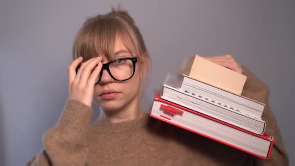 Cute nerd student girl in eyeglasses with stack of books — Stock Video