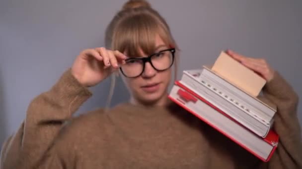 Student girl with stack of books wiping forehead with hand — Stock Video