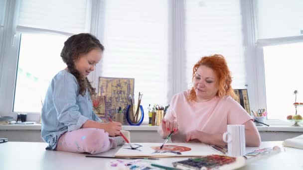 Mãe ajuda a filha pequena bonito para desenhar usando aquarelas — Vídeo de Stock