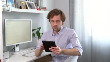 Ofiste sakallı iş adamı tablet kullanıyor.