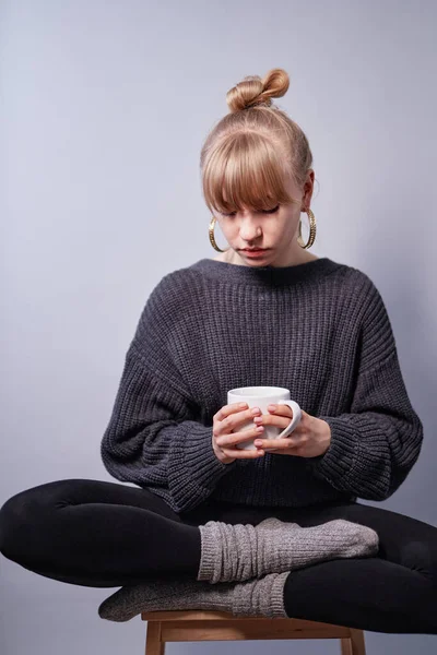 Menina loira em suéter sentado com xícara de café ou chá — Fotografia de Stock