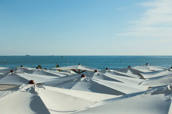 Guarda-chuvas brancos na praia em azul claro céu fundo — Fotografia de Stock