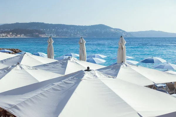 White umbrellas on a beach with mountains on background