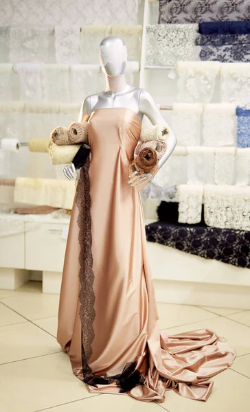 Mannequin en atelier avec tissu beige et rouleaux textiles — Photo
