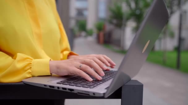 Kvinnliga händer i blus skriva på laptop tangentbord på gatan — Stockvideo