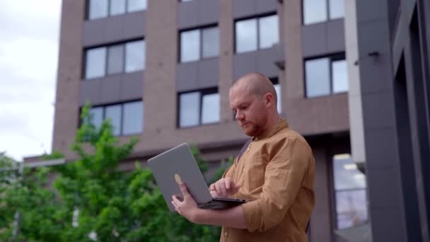 Homem caucasiano de pé na cidade do centro trabalhando em laptop — Vídeo de Stock