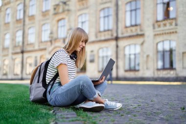Genç liseli kız ya da üniversite öğrencisi dışarıda dizüstü bilgisayar kullanıyor.