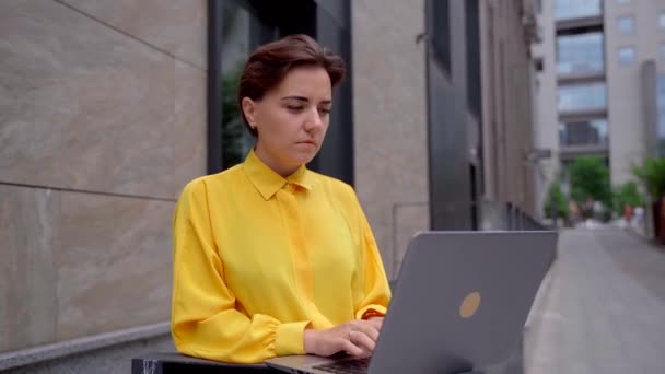 Confident serious businesswoman using laptop outdoor — Stock Video