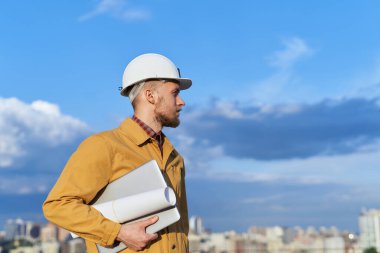 Şehir merkezinin önünde dizüstü bilgisayarlı bir mühendis duruyor.