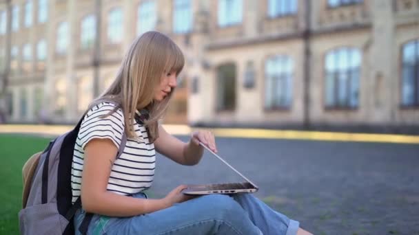 Högskola eller universitetsstudent utomhus med hjälp av bärbar dator på campus — Stockvideo