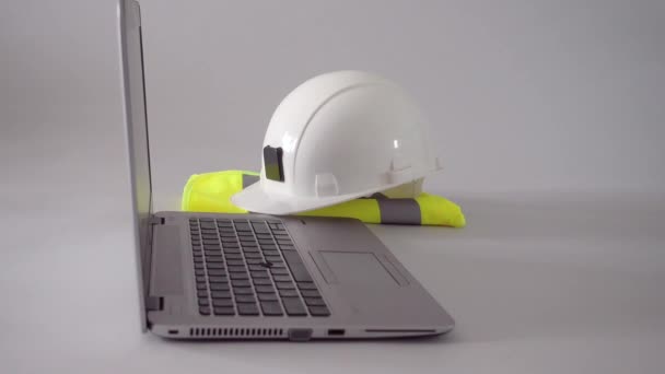 Casque blanc, gilet de sécurité et ordinateur portable avec plans de mise à la main — Video