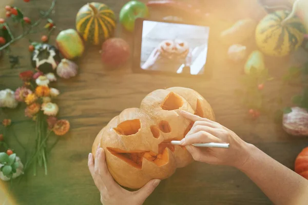 Widok z góry Halloween dyni rzeźbienie przy użyciu instrukcji na tablecie — Zdjęcie stockowe