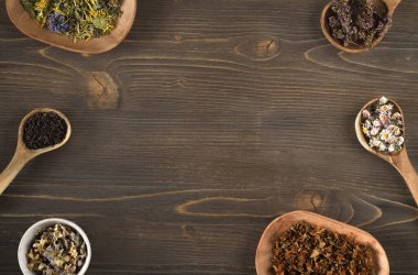 Tahta kaşıklar ve tabaklarda kurumuş bitki çayı çeşitleri.