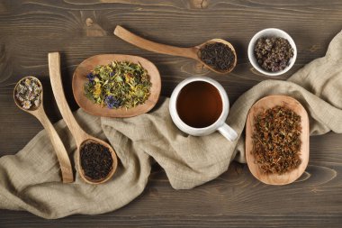 Bir fincan çay ve çay, ahşap kaşıklar ve tabaklar içinde.