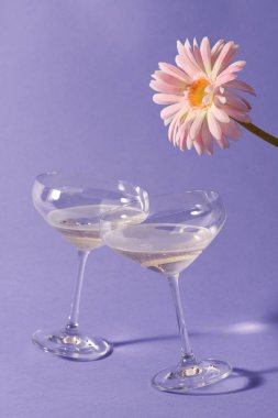 Menekşe arkaplanlı iki kadeh şampanya.