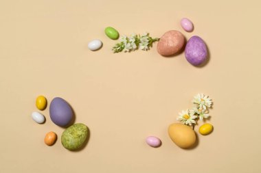 Bej arka planda Paskalya yumurtası ve çiçeklerinin düzenlenmesi