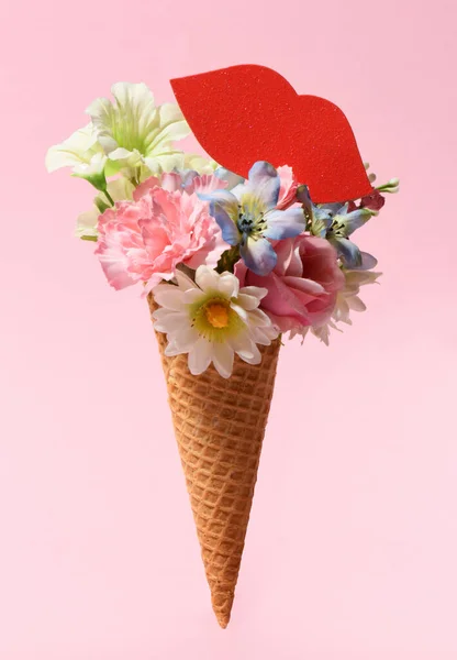 Beautiful bouquet in ice cream cone with red lips on pink background