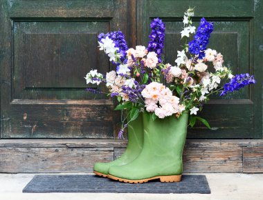 Rubber boots with beautiful flowers near the door